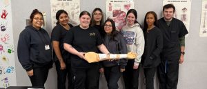 Medical assistant students in Amarillo pose with a mannequin arm wearing a tournequet