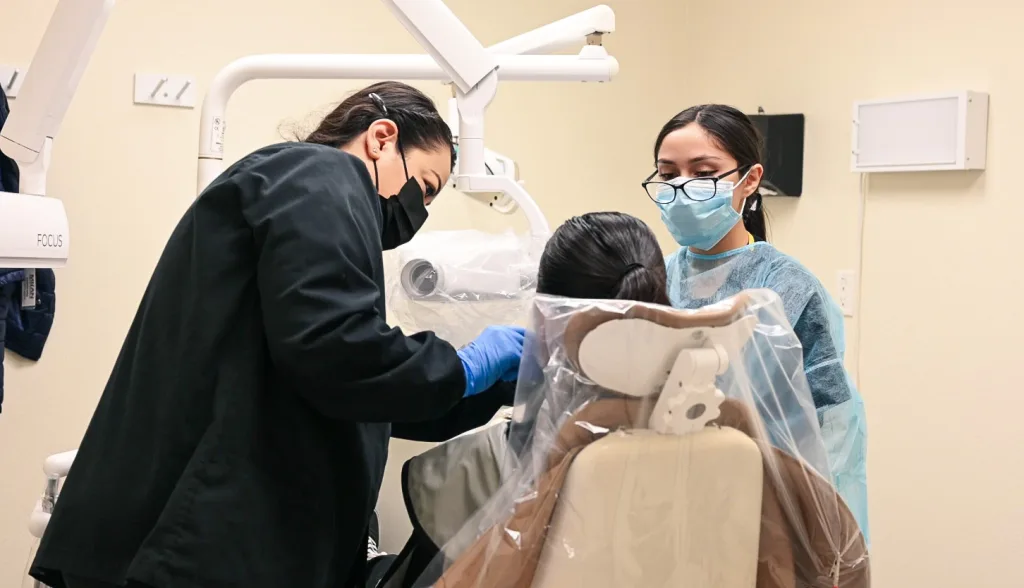 Two students perform an oral cleaning in Merced, California during their dental training program