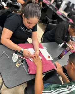 A manicuring student performs a basic manicure to prep one of Eva's Heroes for this week's Fashion Show.